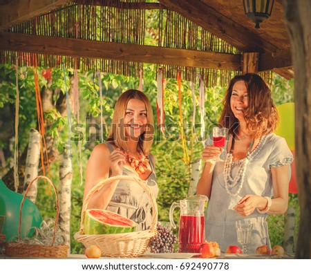 Two beautiful laughing women near a festive table with a wine glass in hands in a pergola outdoors. party. instagram image filter retro style