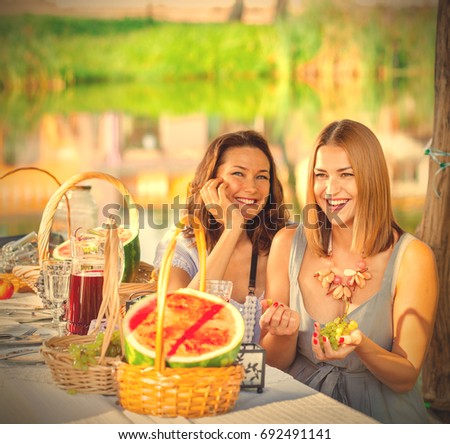 Two beautiful laughing women at a festive table with grapes in hands. instagram image filter retro style