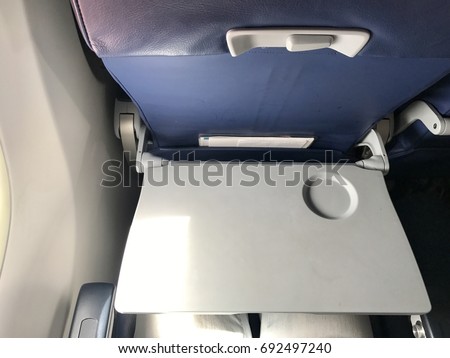 Airplane cabin is all white. All its decorations are necessary stuffs and safety. The gray Tray table for passenger in plane.