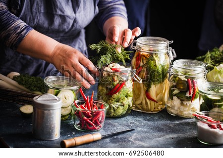 Pickled vegetables in jars displayed on table cauliflower broccoli bean cucumber green tomatoes fermented process glass jars variety copy space Royalty-Free Stock Photo #692506480