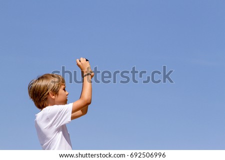 Boy with a digital camera against blue sky