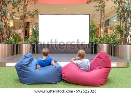 Mock up of blank advertising screen in modern shopping mall. Children looking at big blank digital display