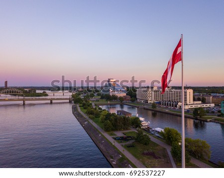 Beautiful aerial sunset view over AB dam in Riga Latvia with a huge flag in the foreground and old town of Riga in the background.