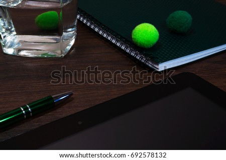 Desk table with supplies. Top view with copy space. Green pen, black tablet, glass of water.