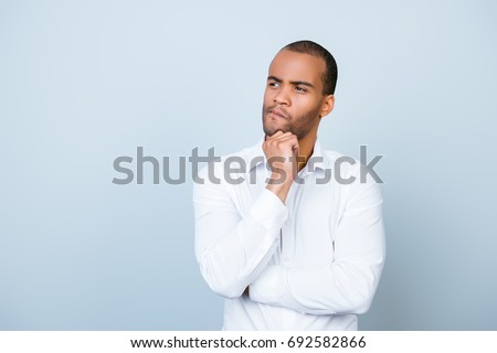 Skeptic, unsure, uncertain, doubts concept. Young african guy in formal wear is looking sceptical, has a grimace of distrust on light blue background Royalty-Free Stock Photo #692582866
