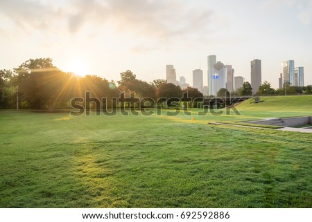 Downtown Houston from Police Memorial park at sunrise with sunbeam/light ray. Green park lawn and modern skylines. The most populous city in Texas, and fourth-most in United States.