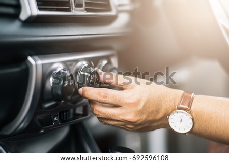 Man Turning on car air conditioning system,finger hitting car emergency light botton,Hand tuning fm radio button in car panel.