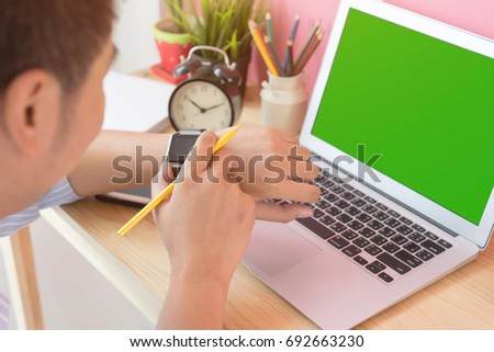 Checking time. Businessman look at smart watch on wrist, working with laptop, green screen workplace at office.