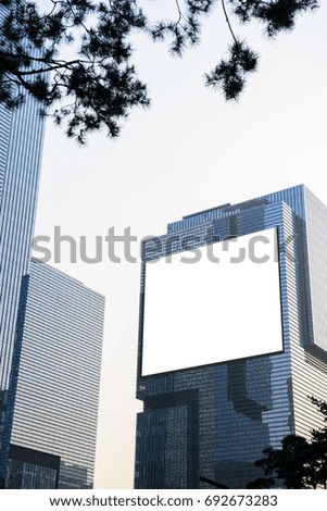 Blank advertising billboard on modern office building in the city with blue sky background useful for products advertisement, street billboard, vertical composition