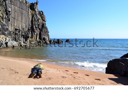Photographer, rocks, sandy beach, clear sea. Cape Isle Fake. Primorye. Russia.