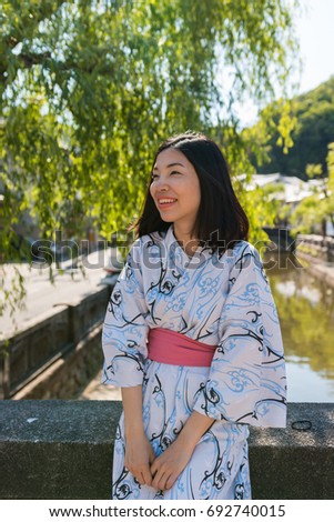 an asian young woman smiling and wearing Yukata, Japanese traditional clothes, under the tree