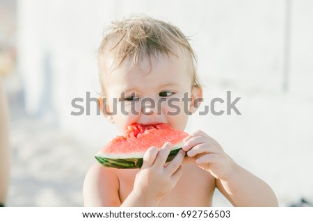 The little boy, shirtless shirtless eating watermelon while on vacation