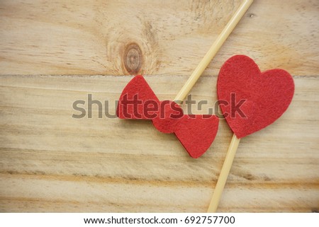 Top or flat lay view of Photo booth props a red heart shape and red bow tie shape on a wooden background flat lay. Birthday parties and weddings.