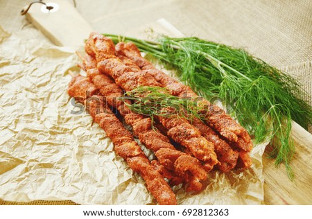 BBQ Pork Belly Strips with Spicy powder and Dill on white paper and wooden broad on sack background.