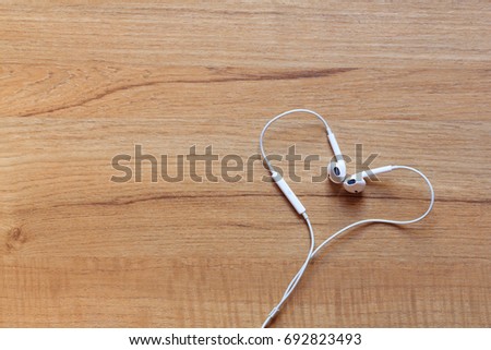 Smart phone on the wooden floor with line heart-shaped earphones, Top view.