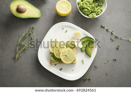 Tasty breakfast toast with avocado and lemon on table