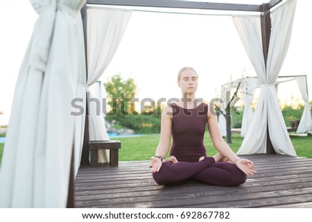 Young girl doing yoga or fitness exercise outdoor in nature with beautiful sky landscape, Namaste pose. Meditation and Relax, freedom concept