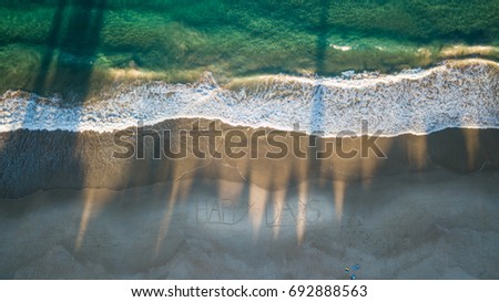 Photograph taken from above, a drone shot looking over the beach with in the sand HAPPY DAYS written.