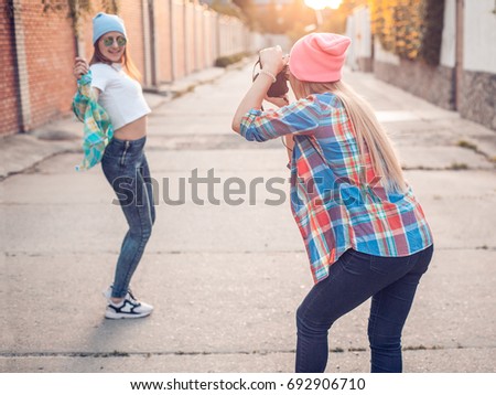 Young woman is taking picture of another woman.