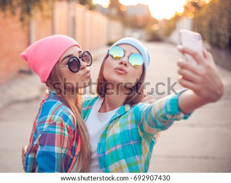 Best friends are taking selfie on phone on the street.