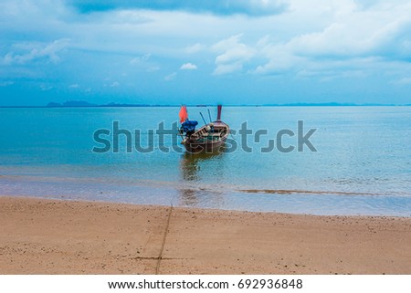 Fishing boat with a coracle boat stored on deck. Close-up of colorful blue boat with red trim. Reflection in water. Fishing is an important industry