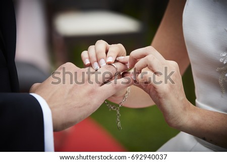 Bride putting ring on groom's finger. Heterosexual couple. Newlyweds. Horizontal format. Vignette. Close up picture. Unrecognizable people. 