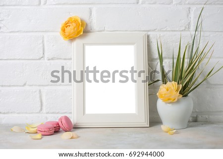 Mockup of picture frame decorated with macaroons and yellow roses on white brick background. empty space for text.