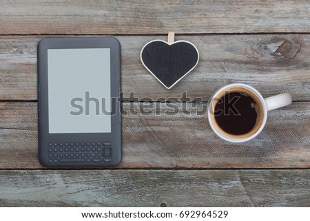 Empty coffee mug, ebook reader and heart shaped sign on wood  table with copy space