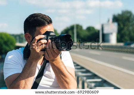 Young man with professional camera photographing outside.