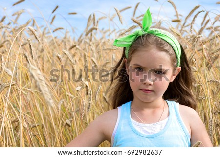 Beautiful girl on a wheat field background on a warm summer day