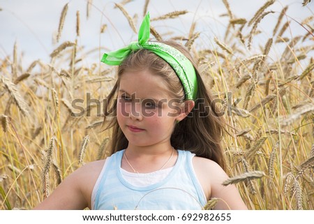 Beautiful girl on a wheat field background on a warm summer day