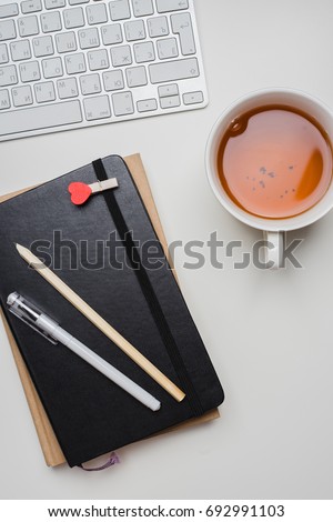 Notebook, keyboard and stationery on white table. Top view of the workplace.