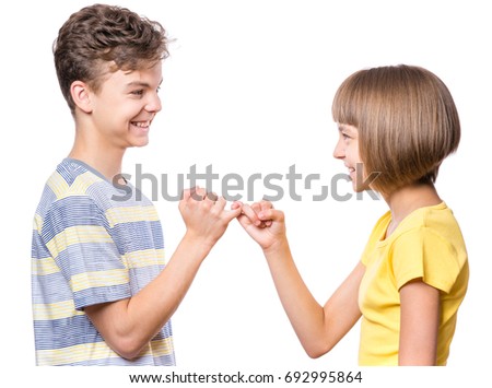 Teen boy and girl on the little finger, hands making promise as a friendship concept. Portrait of happy brother and sister, isolated on white background. 