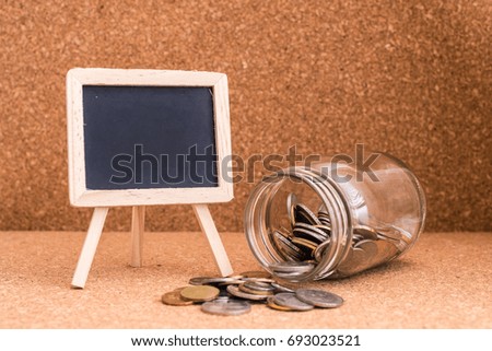 Finance Concept - A jar of coins and a blank blackboard for text. Wood Background. Shallow depth of field.