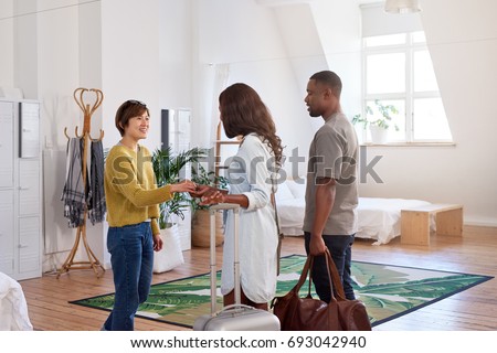Asian woman welcomes black couple into her house home accommodation for their holiday vacation trip
