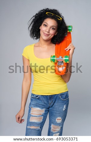 Happy smiling mixed race african american - caucasian female in distressed jeans with skateboard