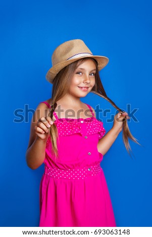 Portrait of young cute girl in pink dress and hat on blue background .Summer vacation and travel concept