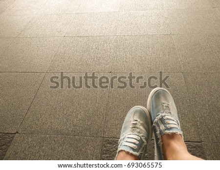 Women wears her light denim sneakers on tiled floor 