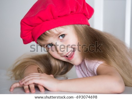 Beautiful little blonde hair girl, has happy fun smiling face, big pretty eyes, long blonde hair, red hat. Child portrait. Creative concept. Close up. Fashion style girl.