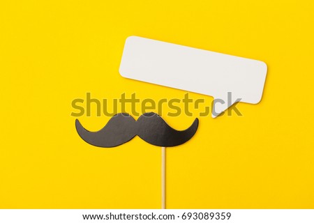 Moustache on a stick with a speech bubble on a bright yellow background Royalty-Free Stock Photo #693089359