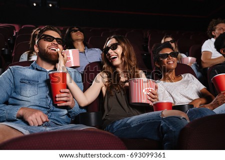 Photo of happy friends sitting in cinema watch film eating popcorn and drinking aerated sweet water.