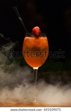 Cocktail drink with strawberry on the table In the smoke on black background. Space in background for copy, text, your words