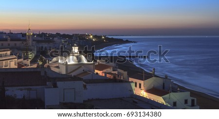 beautiful panoramic night view of Albufeira city in region of Algarve, Portugal. Colorful scene with the beach, sea, street lights at night and sunrise sky.