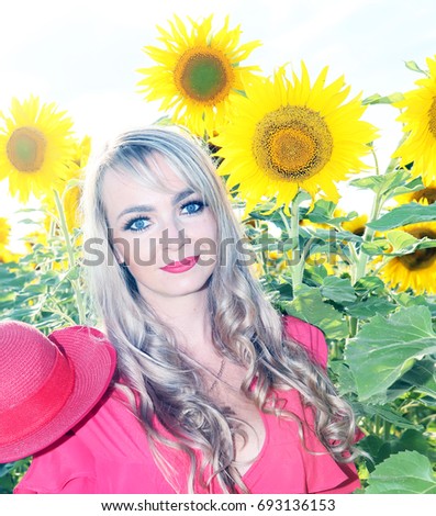 Portrait of beautiful young blonde with yellow sunflowers in pink summer dress