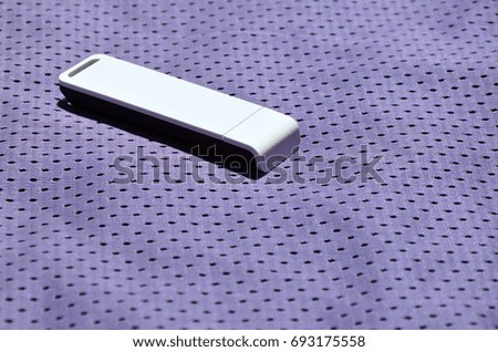 A modern portable USB wi-fi adapter is placed on the violet sportswear made of polyester nylon fiber