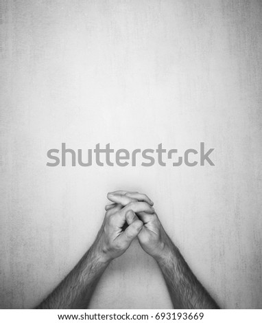 hands of a man are folded into a lock on a gray background, top view. black and white photo, mock up for text, phrases, lettering