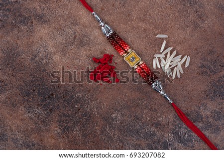 Raksha Bandhan : Rakhi with rice grains and kumkum on stone background, Traditional Indian wrist band which is a symbol of love between Brothers and Sisters.