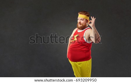 Funny fat man in sports clothes shows his hand okay. 