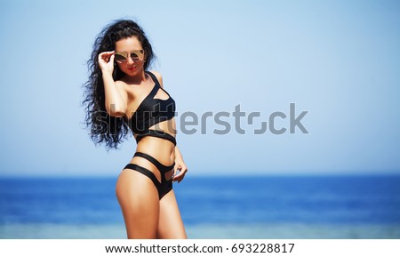 One woman in a bikini walking through a shallow sea on a sunny day. Girl in sea. Beach vacation. Hot summer day. 