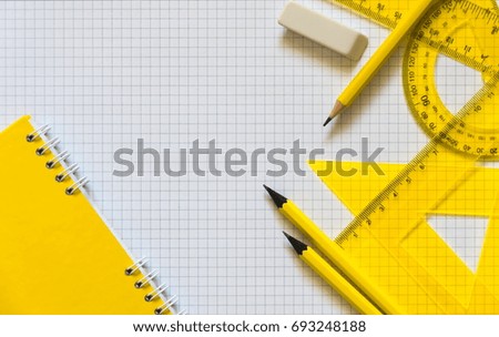 School background. School supplies are yellow on the background of a notebook. Top view